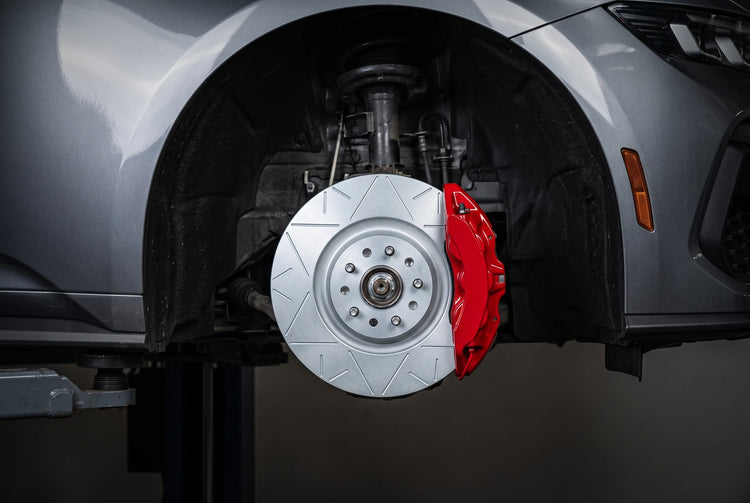 SP Performance peak brake rotor in silver zinc with a red caliper, installed on a car on a shop lift