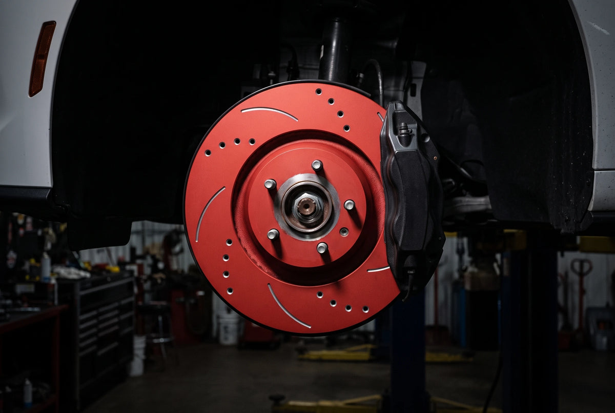 Close-up of an SP Performance double drilled and slotted brake rotor in red zinc showing the chamfered holes and curved slots