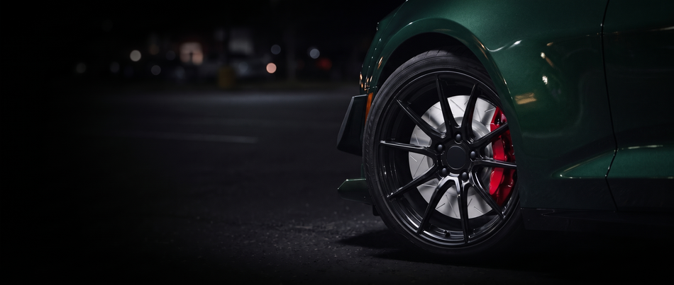 SP Performance peak brake rotor in silver zinc with a red caliper, seen through the wheel of a car at night