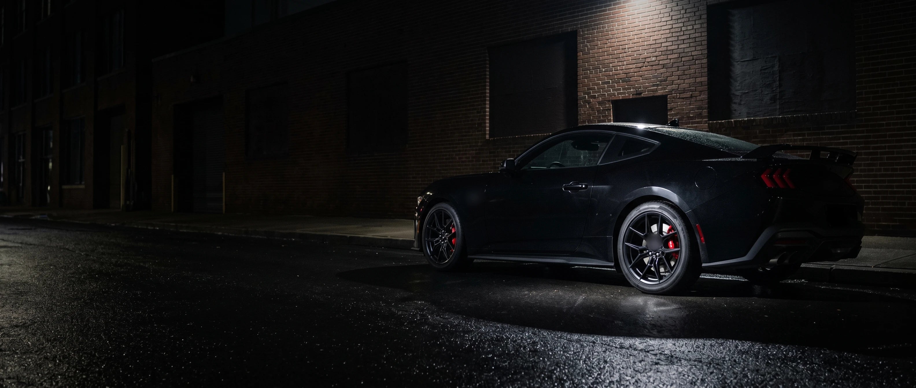 Black Mustang on a wet street at night with Peak surface rotors
